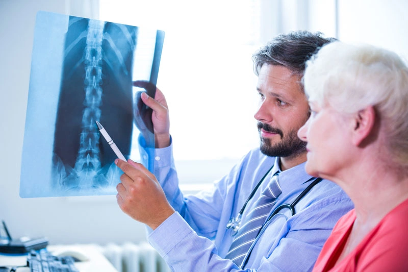 доктор показывает пациентке с межпозвоночной грыжей рентгеновский снимок
